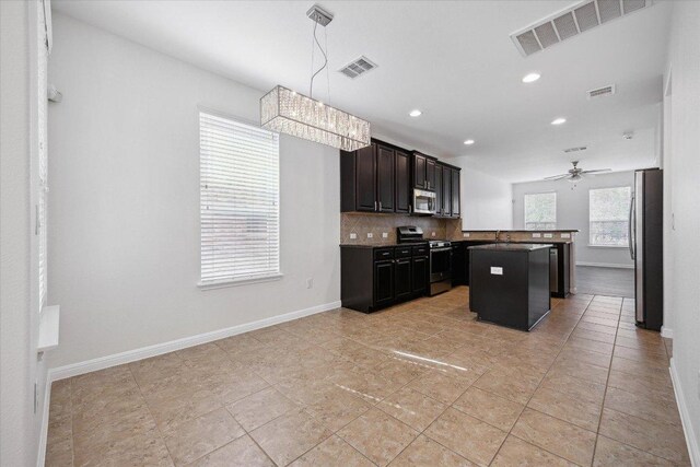 kitchen with appliances with stainless steel finishes, tasteful backsplash, a kitchen island, recessed lighting, and a ceiling fan