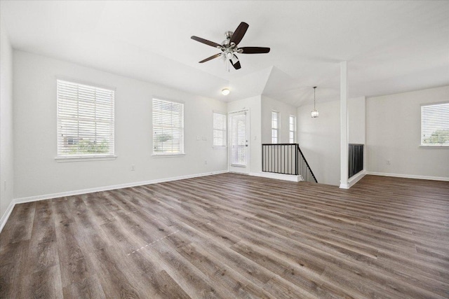unfurnished living room featuring healthy amount of natural light, wood finished floors, baseboards, and lofted ceiling