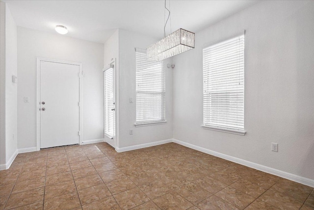 entrance foyer featuring a chandelier and baseboards