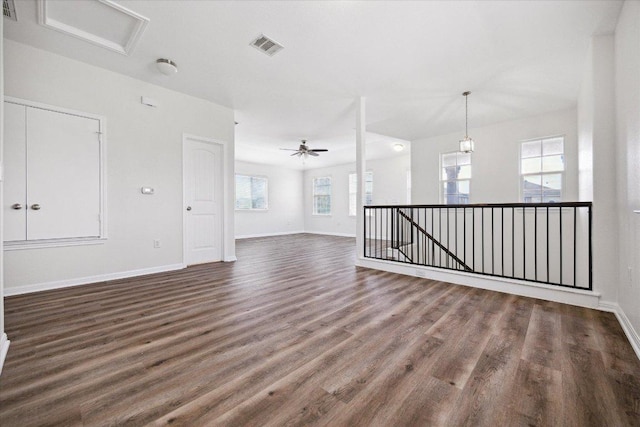 unfurnished living room featuring wood finished floors, baseboards, a ceiling fan, and attic access
