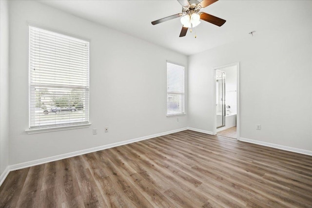 spare room featuring healthy amount of natural light, wood finished floors, a ceiling fan, and baseboards