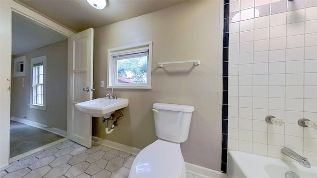 full bath with toilet, plenty of natural light, and tile patterned floors