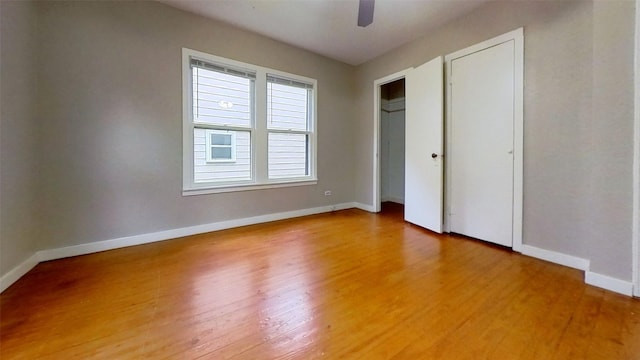 unfurnished bedroom featuring light wood-type flooring, baseboards, multiple closets, and ceiling fan