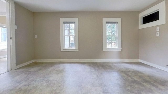 unfurnished room featuring plenty of natural light and baseboards