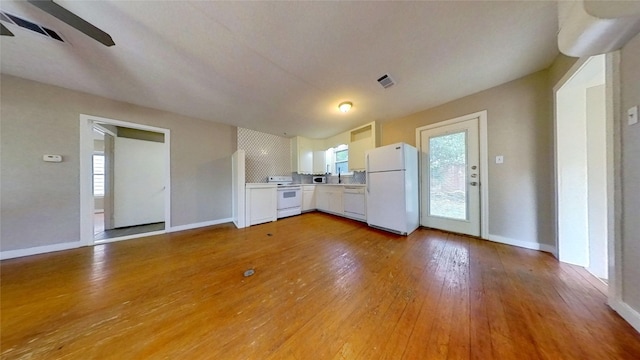 kitchen with white appliances, white cabinetry, light wood finished floors, and baseboards
