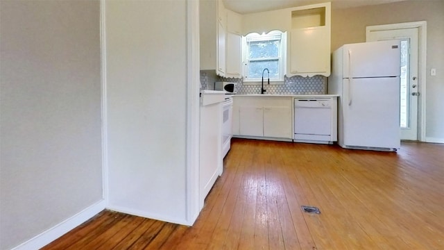 kitchen with white appliances, hardwood / wood-style floors, a sink, light countertops, and white cabinets