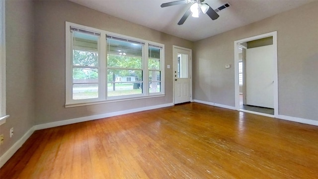 spare room featuring baseboards, wood finished floors, and a ceiling fan