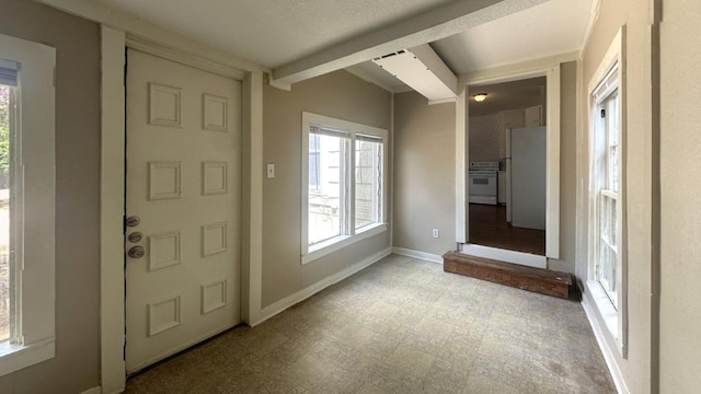 foyer entrance with light flooring, baseboards, healthy amount of natural light, and beam ceiling
