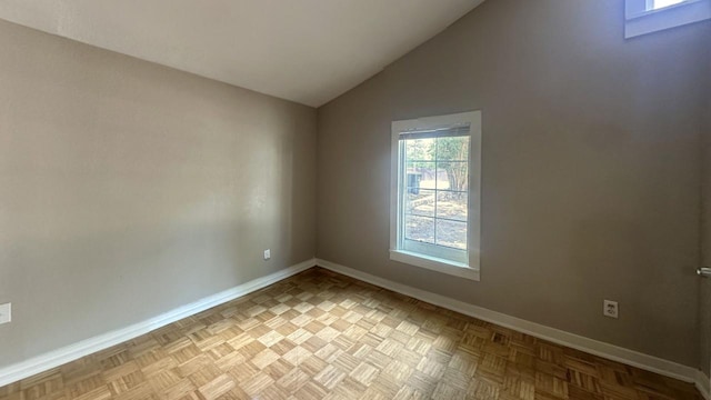 spare room featuring baseboards and lofted ceiling