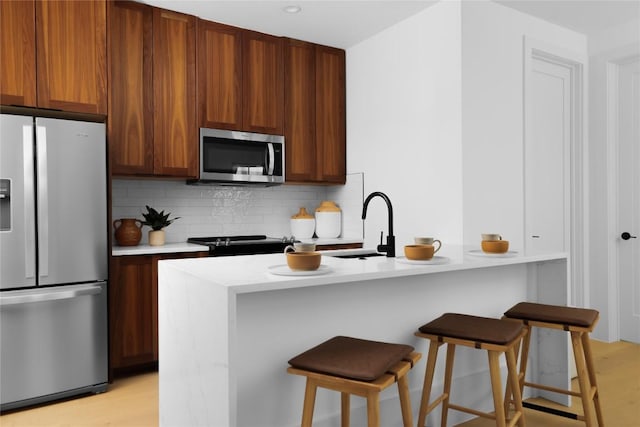 4405 Hennig Dr, Austin, TX 78738 - kitchen with stainless steel appliances, backsplash, light countertops, a kitchen breakfast bar, and light wood finished floors