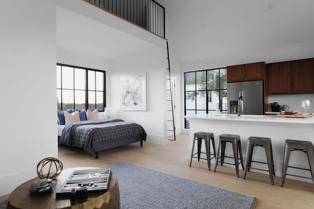 4405 Hennig Dr, Austin, TX 78738 - bedroom featuring stainless steel refrigerator with ice dispenser, light wood finished floors, baseboards, and a towering ceiling