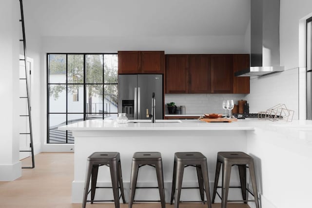 4405 Hennig Dr, Austin, TX 78738 - kitchen featuring appliances with stainless steel finishes, wall chimney exhaust hood, light countertops, a kitchen bar, and decorative backsplash