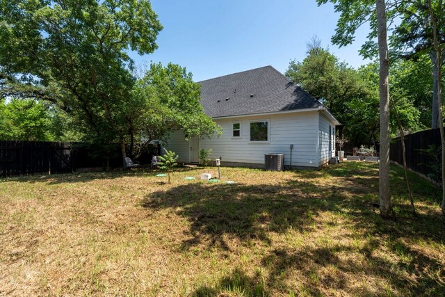rear view of property featuring central AC and roof with shingles