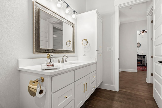 bathroom featuring wood finished floors, vanity, baseboards, and ceiling fan