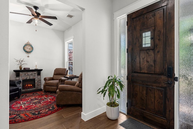 entryway featuring dark wood-style flooring, ceiling fan, a fireplace, and baseboards