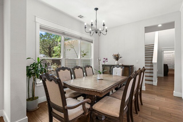 dining area featuring a chandelier, wood finished floors, baseboards, and stairway