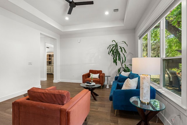 living room with ceiling fan, a tray ceiling, wood finished floors, baseboards, and recessed lighting