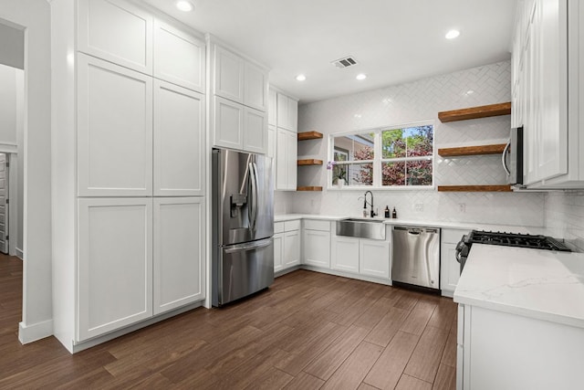kitchen with appliances with stainless steel finishes, open shelves, a sink, dark wood-type flooring, and backsplash