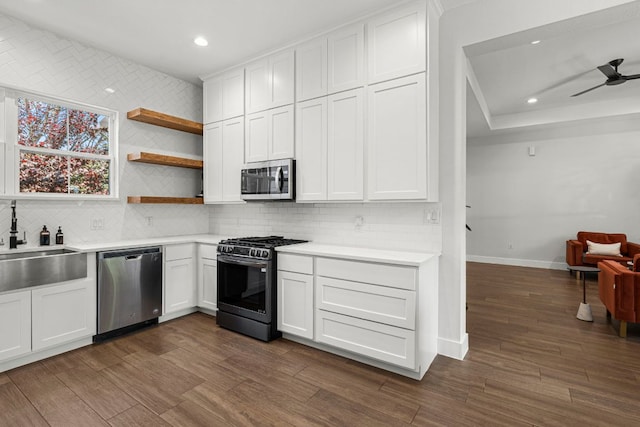 kitchen featuring appliances with stainless steel finishes, a sink, baseboards, tasteful backsplash, and recessed lighting