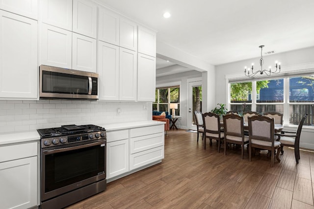 kitchen featuring appliances with stainless steel finishes, a chandelier, light countertops, backsplash, and dark wood-style floors