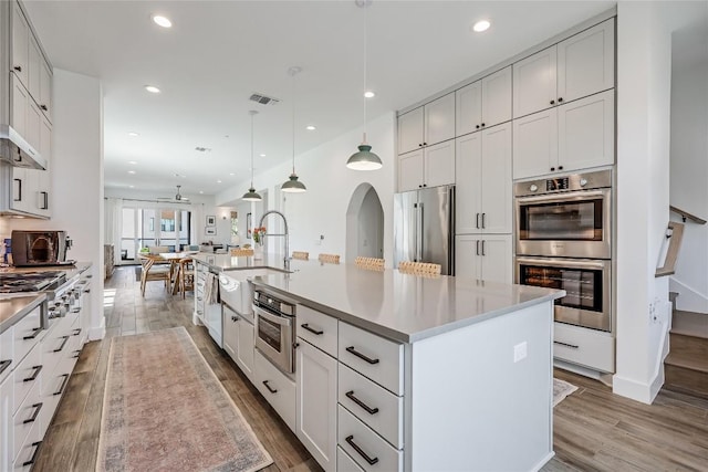 4609 Unity Cir, Austin, TX 78731 - kitchen featuring appliances with stainless steel finishes, a sink, light wood-style floors, a large island with sink, and recessed lighting