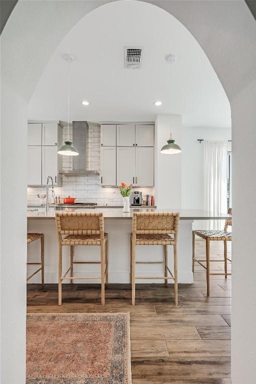 4609 Unity Cir, Austin, TX 78731 - kitchen with a breakfast bar, arched walkways, light wood-type flooring, backsplash, and light countertops
