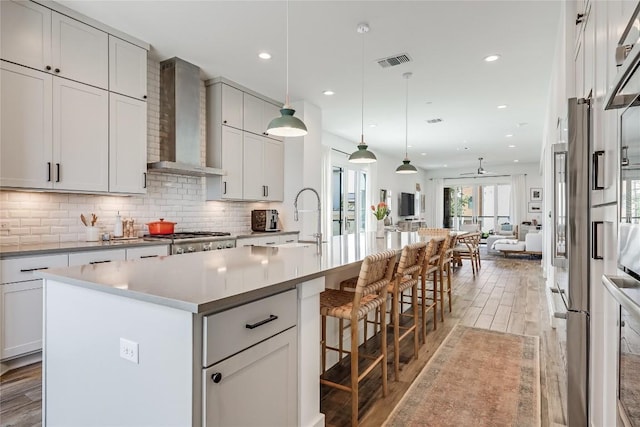 4609 Unity Cir, Austin, TX 78731 - kitchen featuring wall chimney exhaust hood, light wood finished floors, open floor plan, tasteful backsplash, and recessed lighting