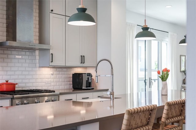 4609 Unity Cir, Austin, TX 78731 - kitchen featuring wall chimney exhaust hood, tasteful backsplash, decorative light fixtures, a kitchen breakfast bar, and white cabinets