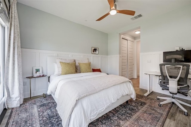 4609 Unity Cir, Austin, TX 78731 - bedroom featuring wainscoting, an office area, wood finished floors, a decorative wall, and a ceiling fan