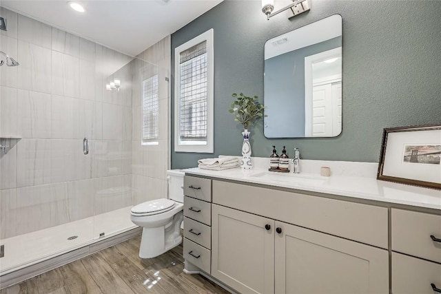 4609 Unity Cir, Austin, TX 78731 - full bathroom featuring toilet, vanity, a shower stall, wood finished floors, and a textured wall