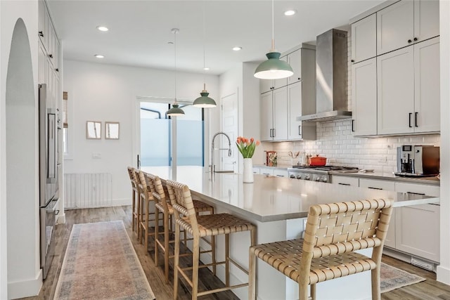 4609 Unity Cir, Austin, TX 78731 - kitchen featuring wall chimney exhaust hood, light wood-style floors, backsplash, a sink, and a kitchen bar