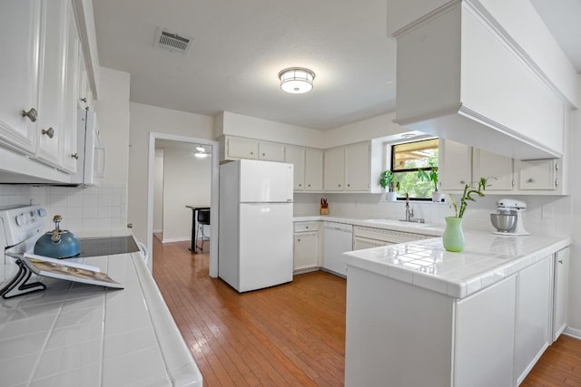 315 Juniper Dr, Mountain City, TX 78610 - kitchen with white appliances, a sink, a peninsula, backsplash, and light wood-style flooring
