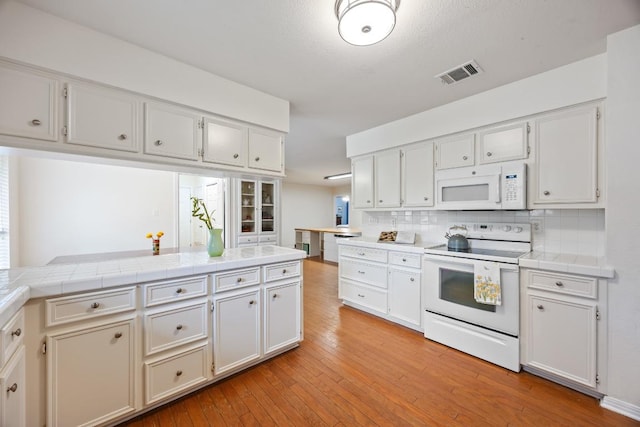 315 Juniper Dr, Mountain City, TX 78610 - kitchen with white appliances, tasteful backsplash, light wood-style floors, and tile counters