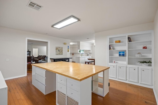 315 Juniper Dr, Mountain City, TX 78610 - kitchen with white cabinetry, wood-type flooring, a center island, and light countertops