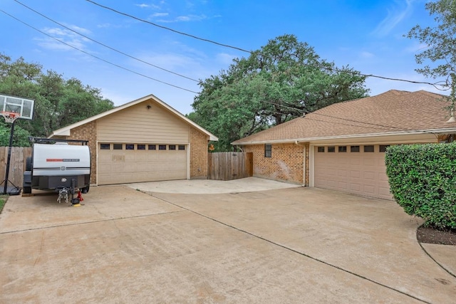 315 Juniper Dr, Mountain City, TX 78610 - view of property exterior featuring a detached garage, fence, brick siding, and an outbuilding