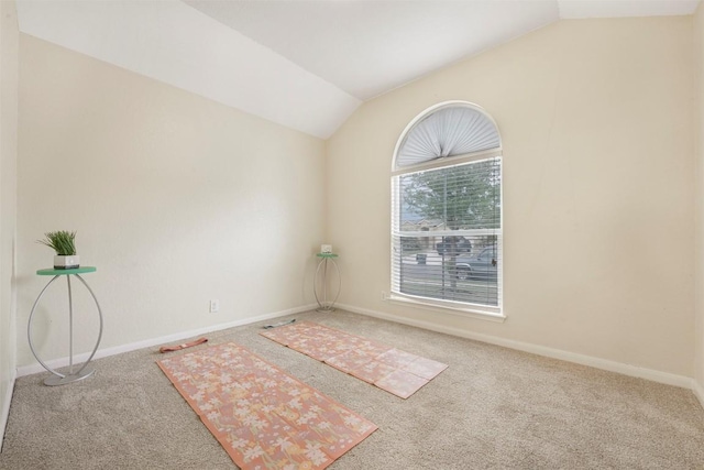 carpeted empty room featuring vaulted ceiling and baseboards