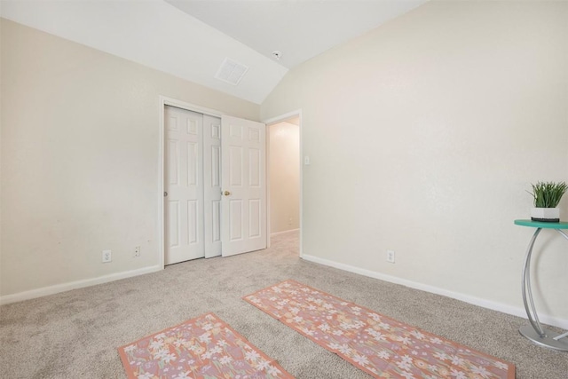 unfurnished bedroom featuring carpet flooring, lofted ceiling, baseboards, and a closet