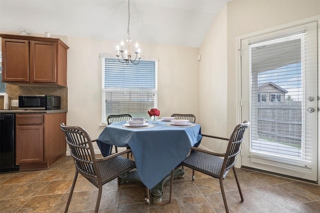 dining space featuring a chandelier, lofted ceiling, and dark stone finish flooring