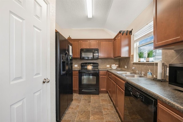 kitchen featuring black appliances, a sink, lofted ceiling, backsplash, and brown cabinets
