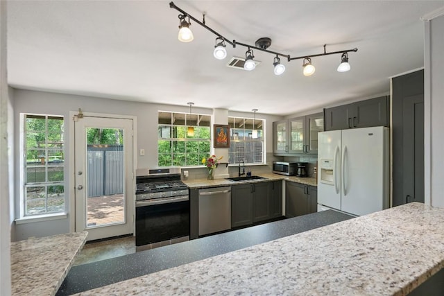 5900 Nasco Dr, Austin, TX 78757 - kitchen with appliances with stainless steel finishes, a sink, glass insert cabinets, and light stone countertops