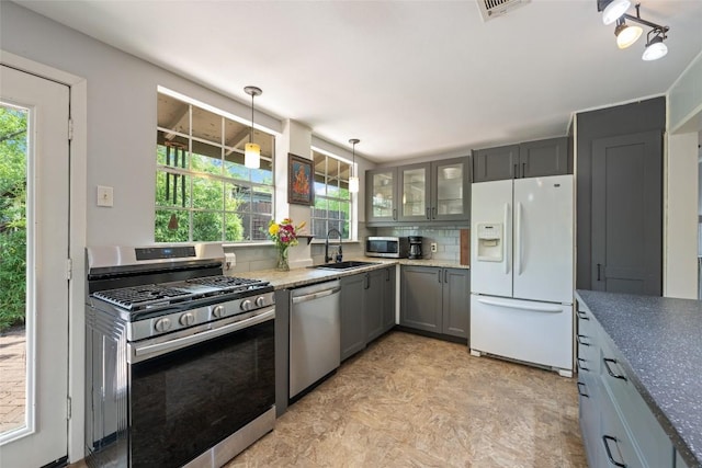 5900 Nasco Dr, Austin, TX 78757 - kitchen with appliances with stainless steel finishes, a sink, gray cabinets, glass insert cabinets, and pendant lighting