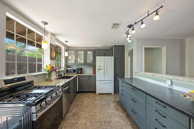 5900 Nasco Dr, Austin, TX 78757 - kitchen with appliances with stainless steel finishes, a sink, glass insert cabinets, decorative light fixtures, and dark stone counters