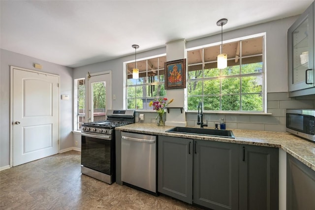 5900 Nasco Dr, Austin, TX 78757 - kitchen with appliances with stainless steel finishes, a sink, gray cabinetry, decorative backsplash, and light stone countertops