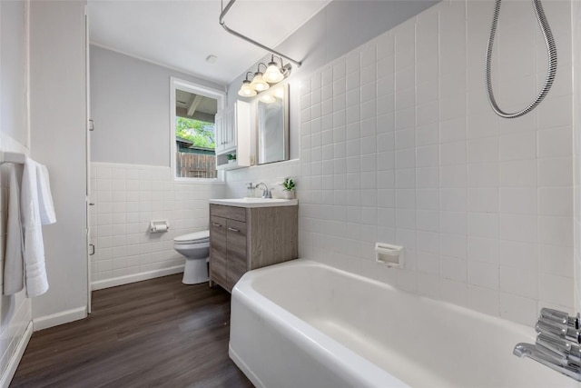 5900 Nasco Dr, Austin, TX 78757 - bathroom featuring tile walls, a tub, wood finished floors, vanity, and toilet