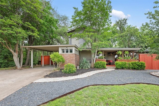 5900 Nasco Dr, Austin, TX 78757 - view of front of house featuring concrete driveway, a carport, covered porch, brick siding, and fence