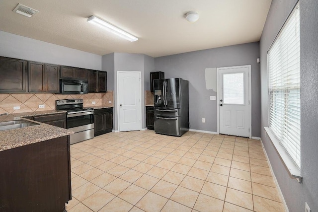 kitchen with black appliances, tasteful backsplash, a sink, dark brown cabinetry, and light tile patterned floors
