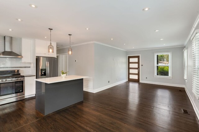 701 Bouldin Ave, Austin, TX 78704 - kitchen featuring wall chimney exhaust hood, appliances with stainless steel finishes, dark wood finished floors, a kitchen island, and white cabinets
