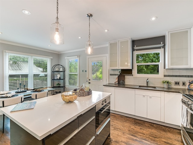 701 Bouldin Ave, Austin, TX 78704 - kitchen featuring stainless steel stove, ornamental molding, decorative backsplash, white cabinets, and dark wood finished floors