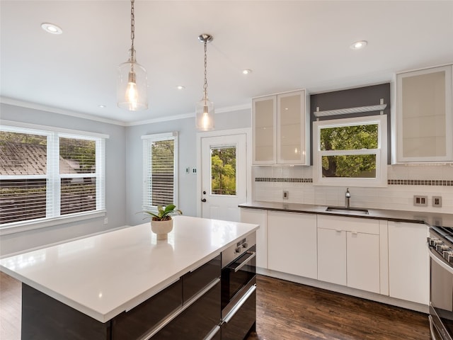 701 Bouldin Ave, Austin, TX 78704 - kitchen with backsplash, stove, glass insert cabinets, crown molding, and dark wood-style floors