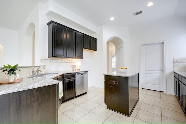 kitchen with dishwasher, a sink, light stone countertops, tasteful backsplash, and light tile patterned floors